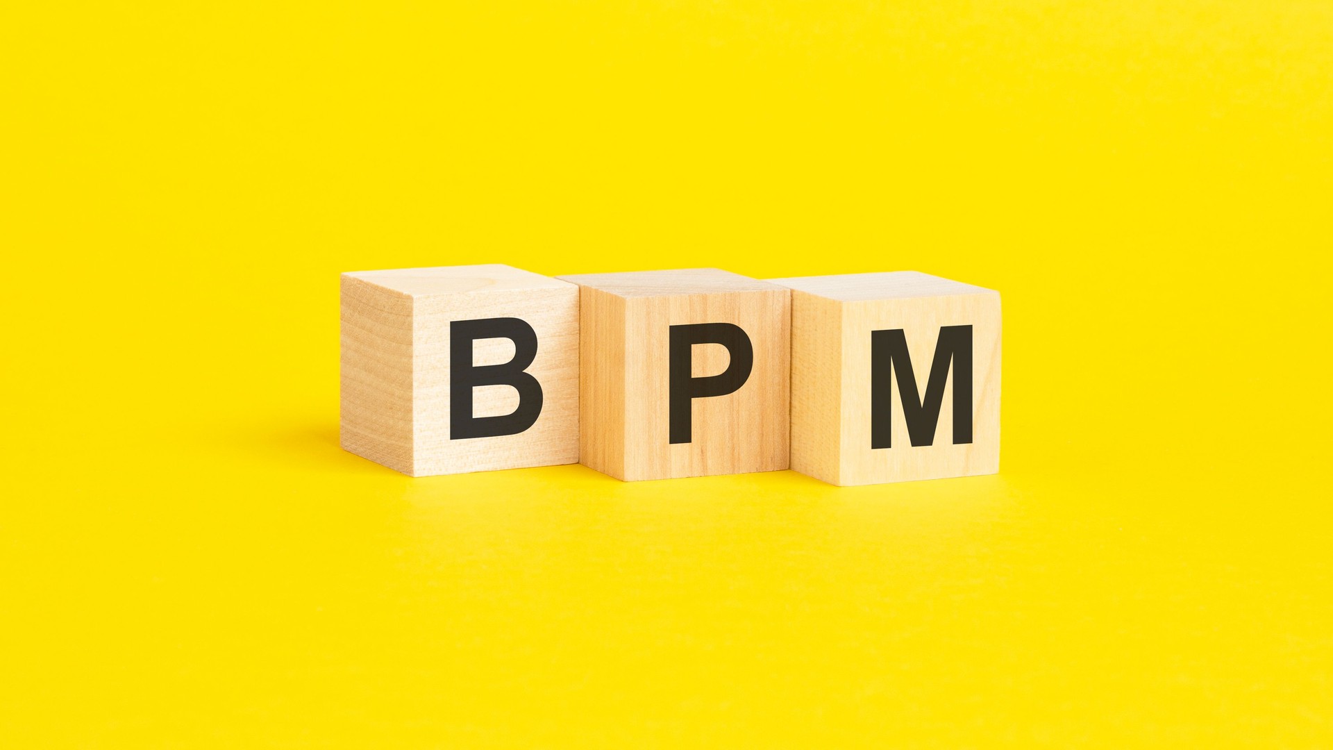 BPM, símbolo de Business Process Management. palabras conceptuales en cubos de madera sobre un hermoso fondo amarillo